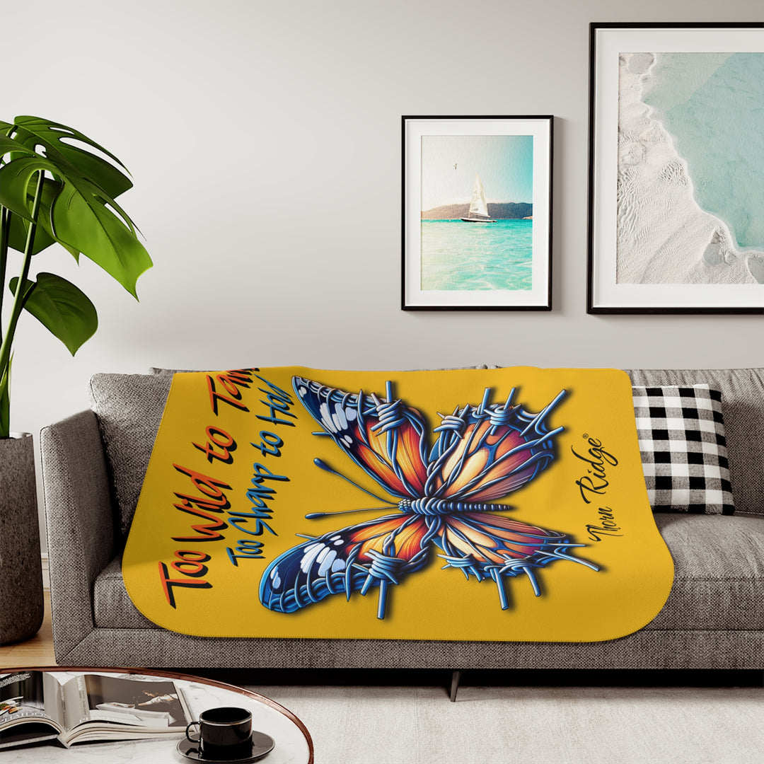 Butterfly design with barbed wire it's wings on a yellow sherpa blanket with text that says Too Wild to Tame Too Sharp to Hold and is the Barbfly legend from Thorn Ridge®