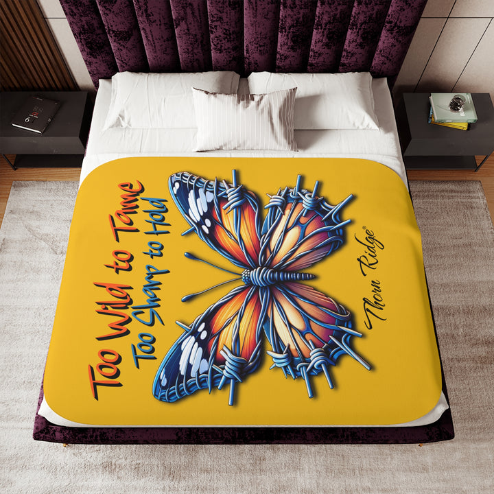 Butterfly design with barbed wire it's wings on a yellow sherpa blanket with text that says Too Wild to Tame Too Sharp to Hold and is the Barbfly legend from Thorn Ridge®