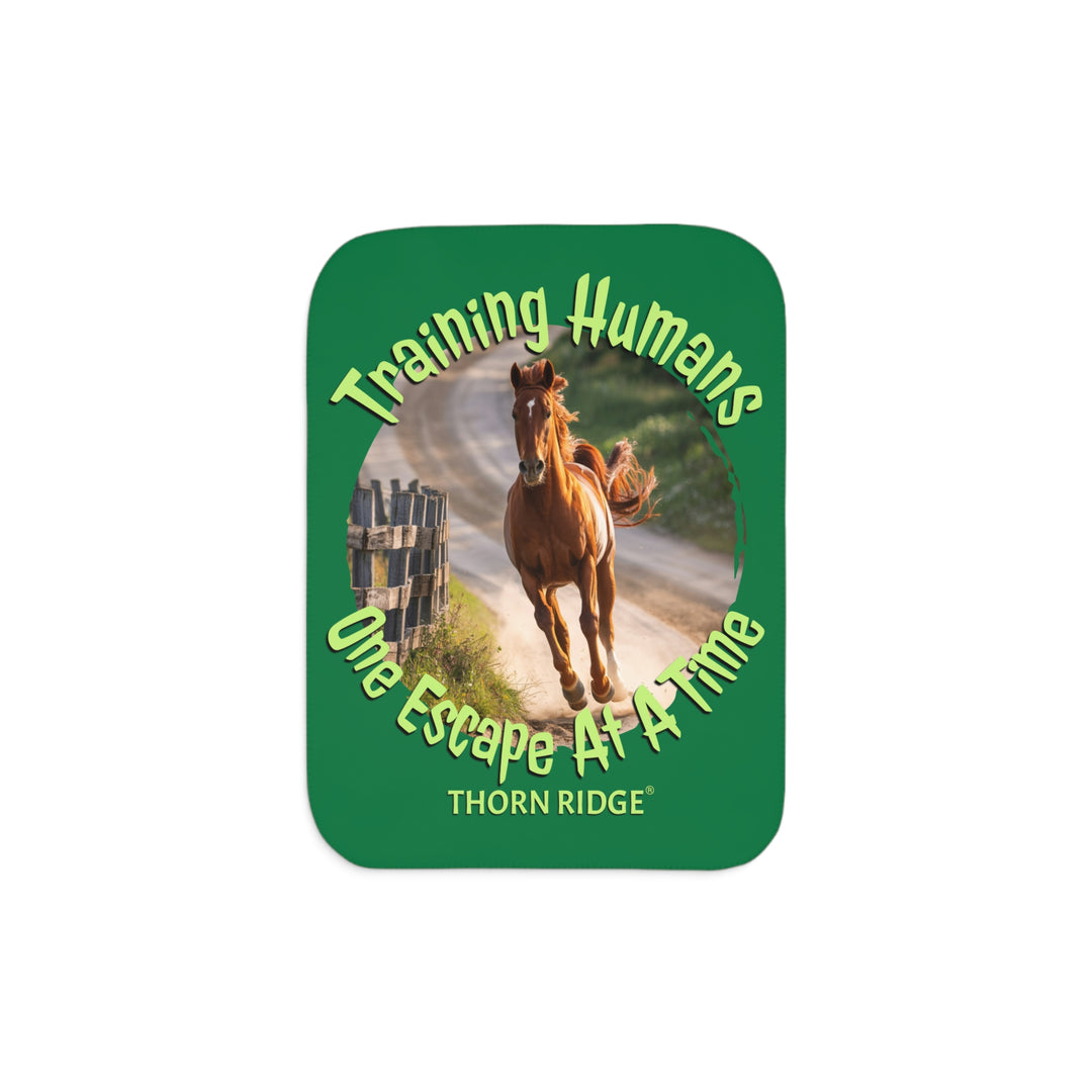 Training Humans One Escape At A Time  green sherpa blanket with the image of a bay horse running down a dirt road alongside a wooden fence. Labeled Thorn Ridge®