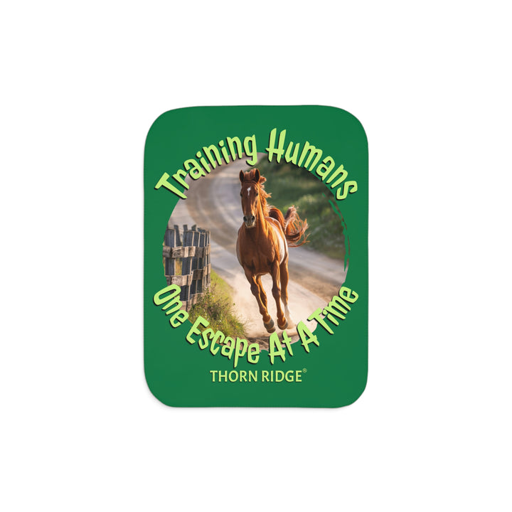 Training Humans One Escape At A Time  green sherpa blanket with the image of a bay horse running down a dirt road alongside a wooden fence. Labeled Thorn Ridge®
