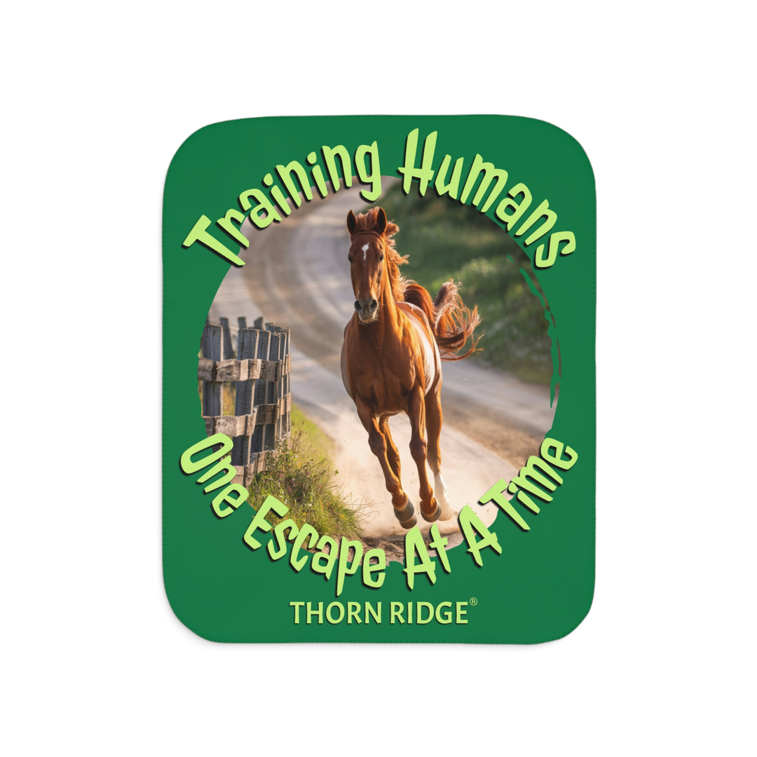 Training Humans One Escape At A Time  green sherpa blanket with the image of a bay horse running down a dirt road alongside a wooden fence. Labeled Thorn Ridge®