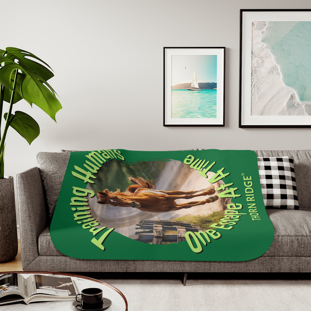 Training Humans One Escape At A Time  green sherpa blanket with the image of a bay horse running down a dirt road alongside a wooden fence. Labeled Thorn Ridge®