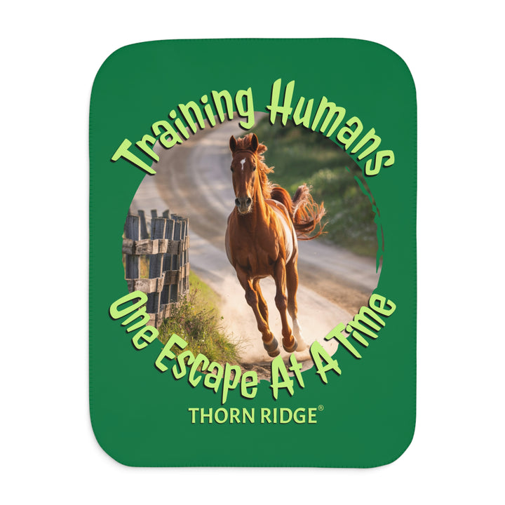 Training Humans One Escape At A Time  green sherpa blanket with the image of a bay horse running down a dirt road alongside a wooden fence. Labeled Thorn Ridge®