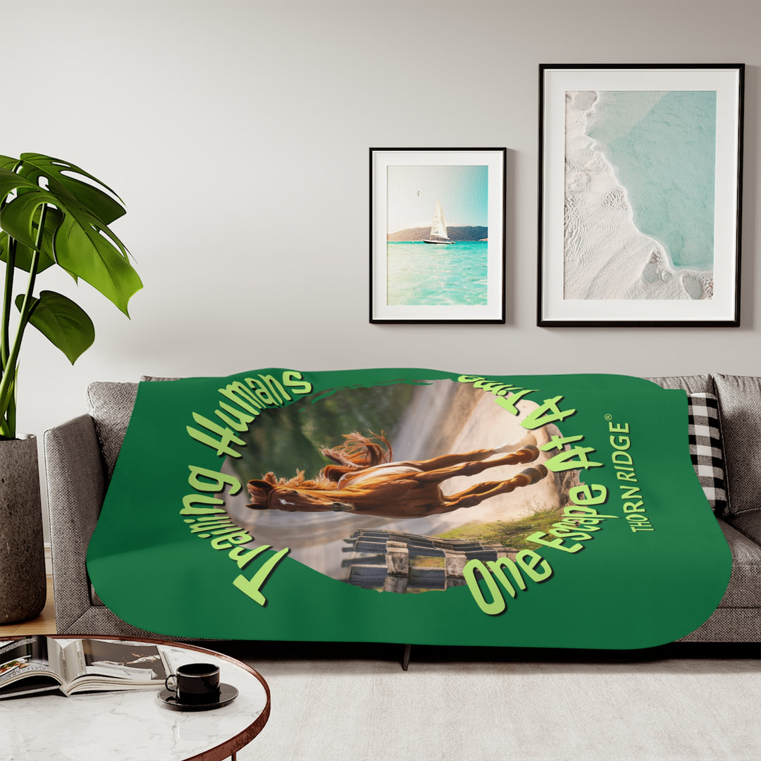 Training Humans One Escape At A Time  green sherpa blanket with the image of a bay horse running down a dirt road alongside a wooden fence. Labeled Thorn Ridge®