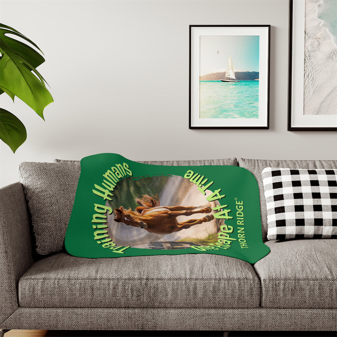 Training Humans One Escape At A Time  green sherpa blanket with the image of a bay horse running down a dirt road alongside a wooden fence. Labeled Thorn Ridge®