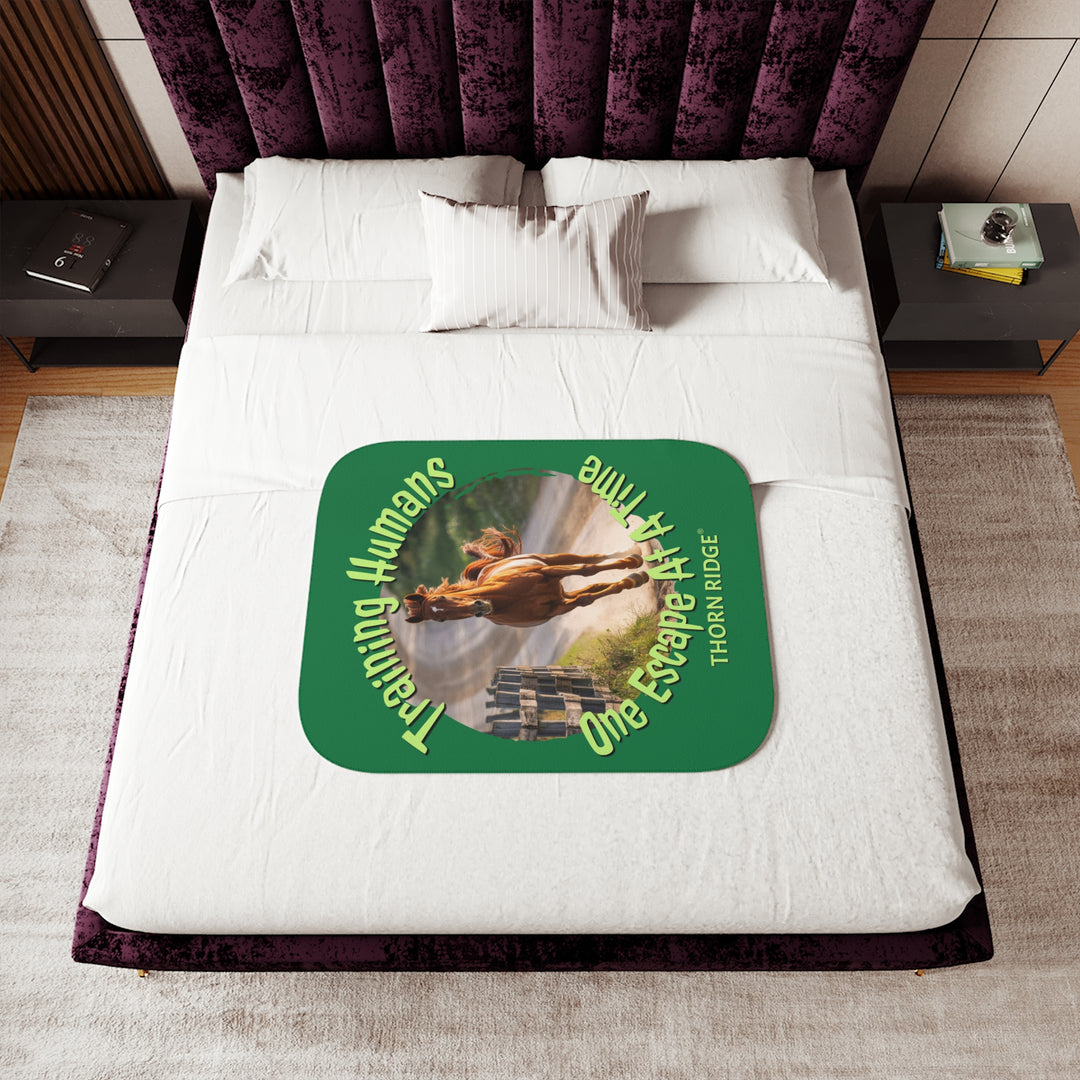 Training Humans One Escape At A Time  green sherpa blanket with the image of a bay horse running down a dirt road alongside a wooden fence. Labeled Thorn Ridge®