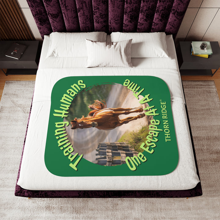 Training Humans One Escape At A Time  green sherpa blanket with the image of a bay horse running down a dirt road alongside a wooden fence. Labeled Thorn Ridge®