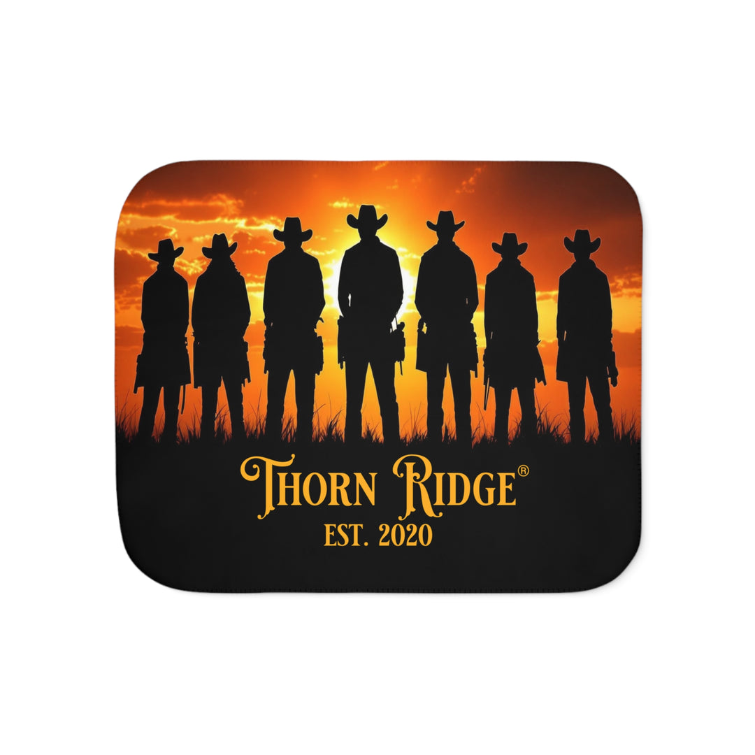 Silhouette of Seven Riders cowboys against an orange sunset with 'Thorn Ridge' branding on a sherpa blanket