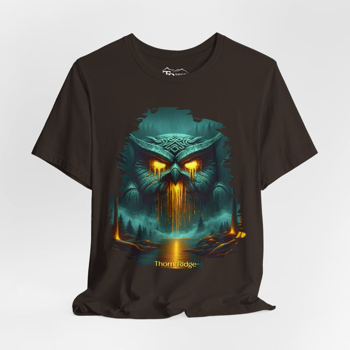 Legend of the Owl King tee by Thorn Ridge with a ancient statue of an owl with glowing lava eyes and mouth in front of a river with fog in the forest. 