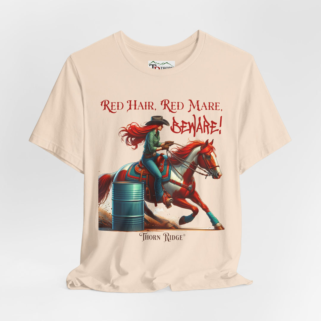 t-shirt with a graphic of a redhead woman on a horse barrel racing and the text 'Red Hair, Red Mare, Beware!' labeled Thorn Ridge®.