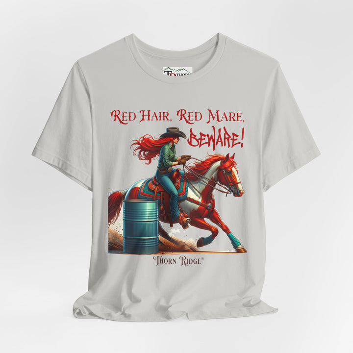 t-shirt with a graphic of a redhead woman on a horse barrel racing and the text 'Red Hair, Red Mare, Beware!' labeled Thorn Ridge®.