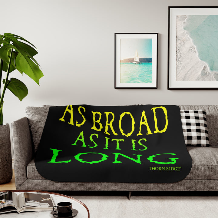 Black sherpa blanket with yellow and green text 'AS BROAD AS IT IS LONG' and 'THORN RIDGE' branding.
