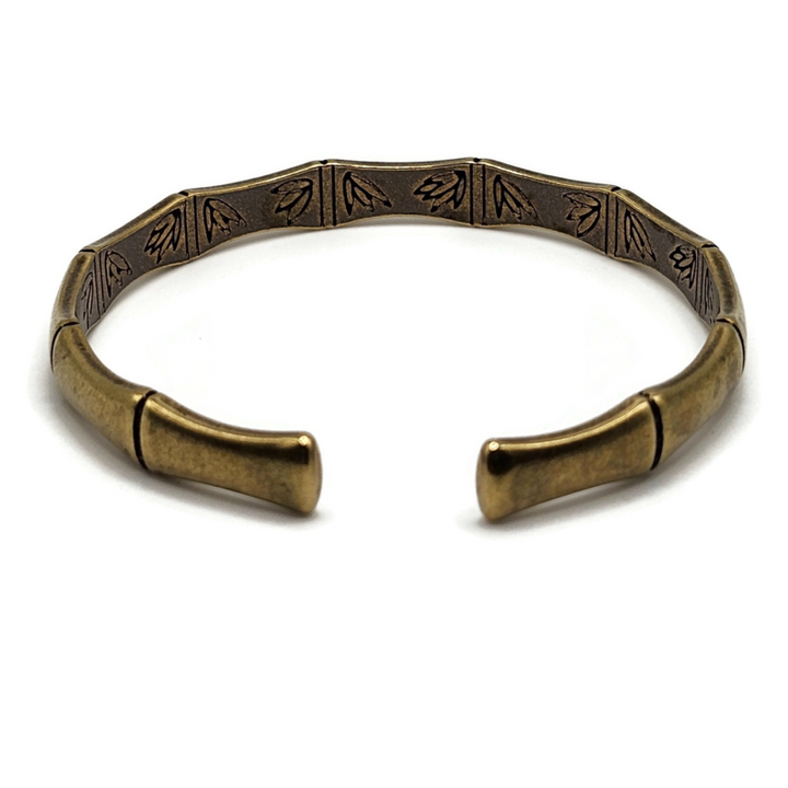 brass and copper Tibetan cuff bracelet is in the shape of bamboo and has images of flowers on the inside