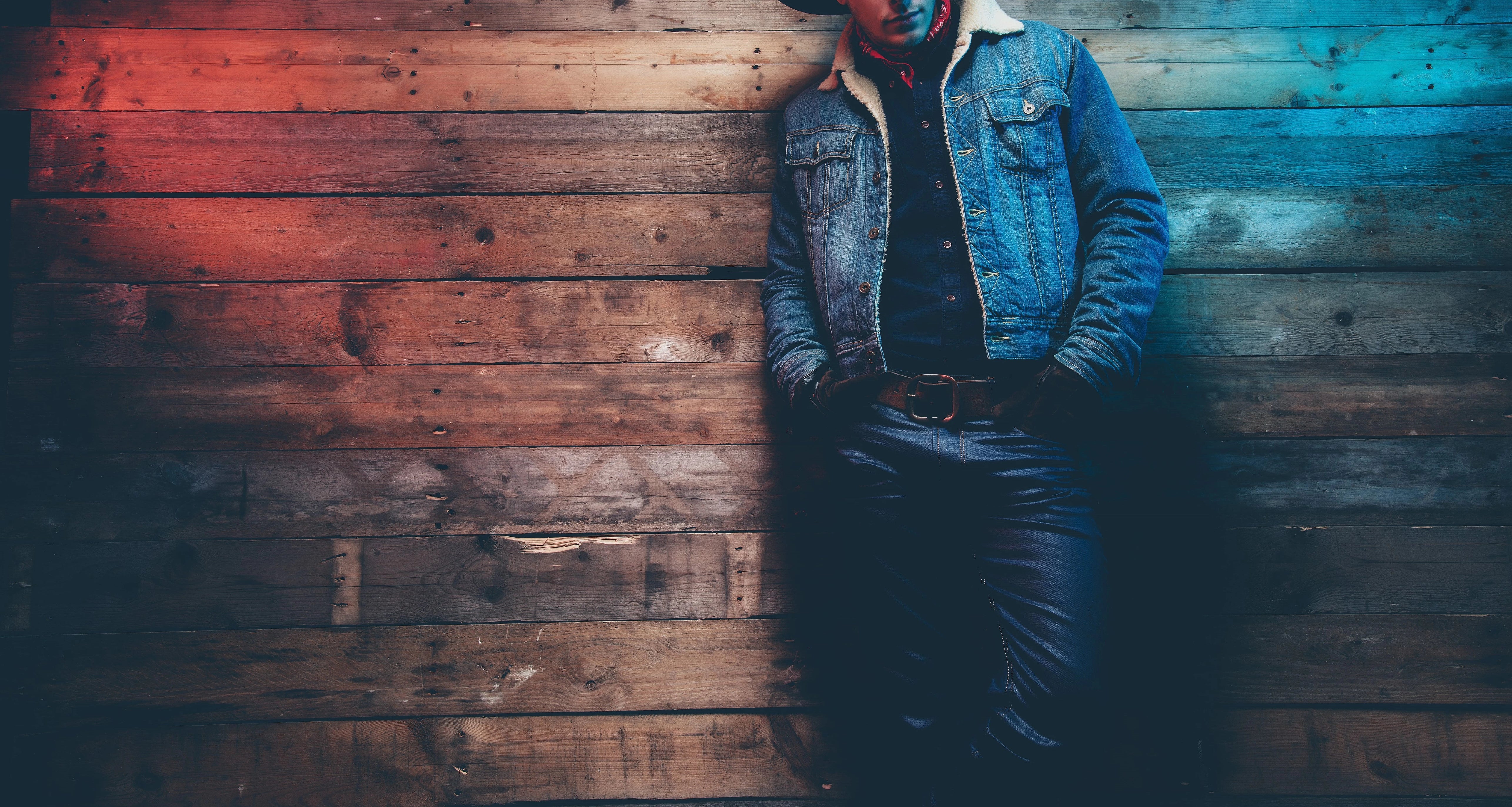 Cowboy leaning on a wooden wall dressed in all denim.