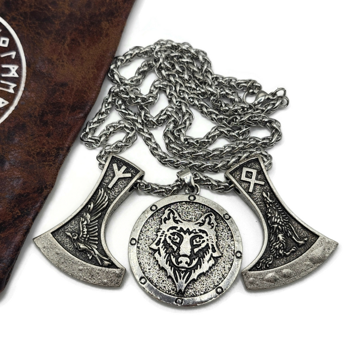 Viking necklace with two axes and a wolf head pendant on a snake chain. Image shows drawsting bag with viking and rune symbols on it. 