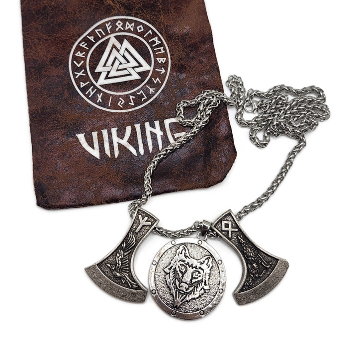 Viking necklace with two axes and a wolf head pendant on a snake chain. Image shows drawsting bag with viking and rune symbols on it. 