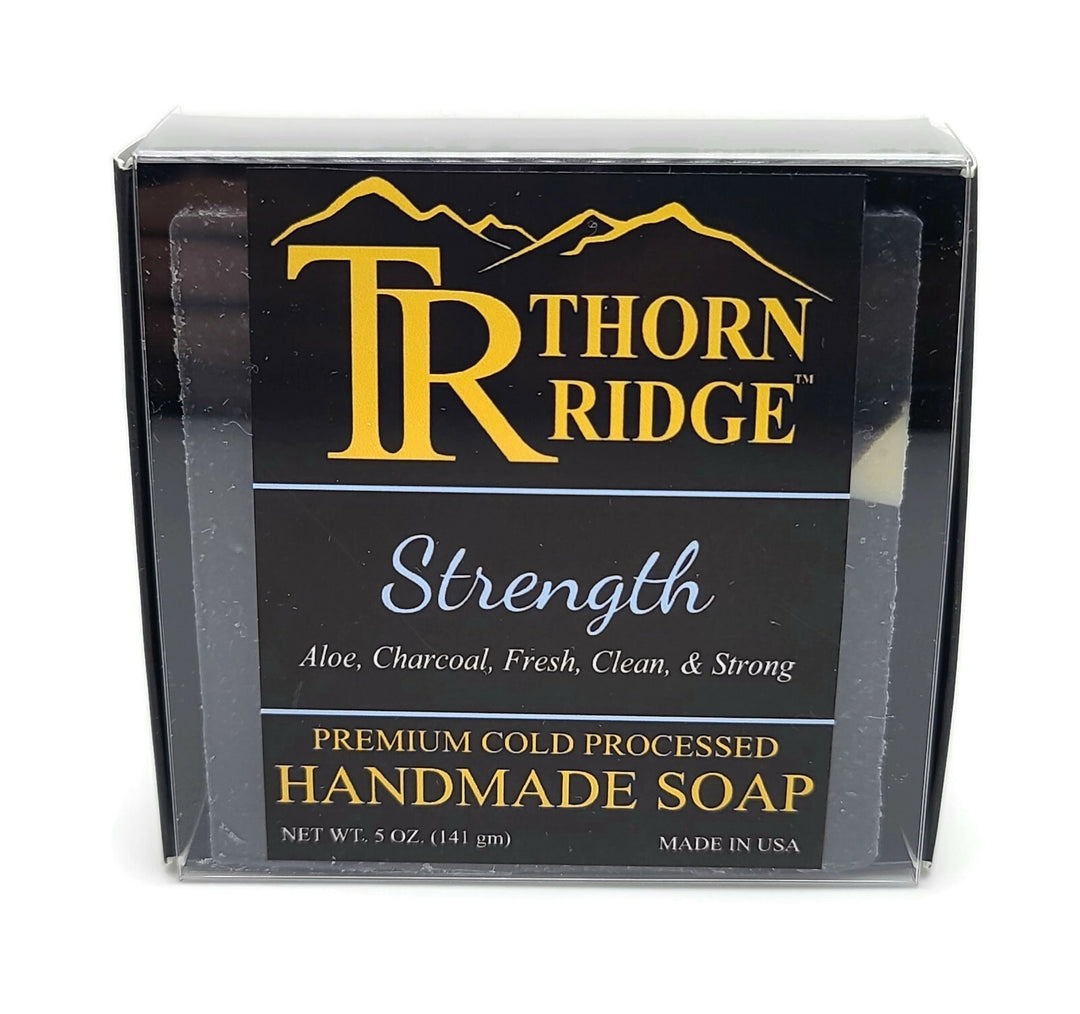 Packaging of Thorn Ridge soap labeled "Strength," described as aloe, charcoal, clean and strong, premium cold processed, handmade, 5 oz. Made in USA.