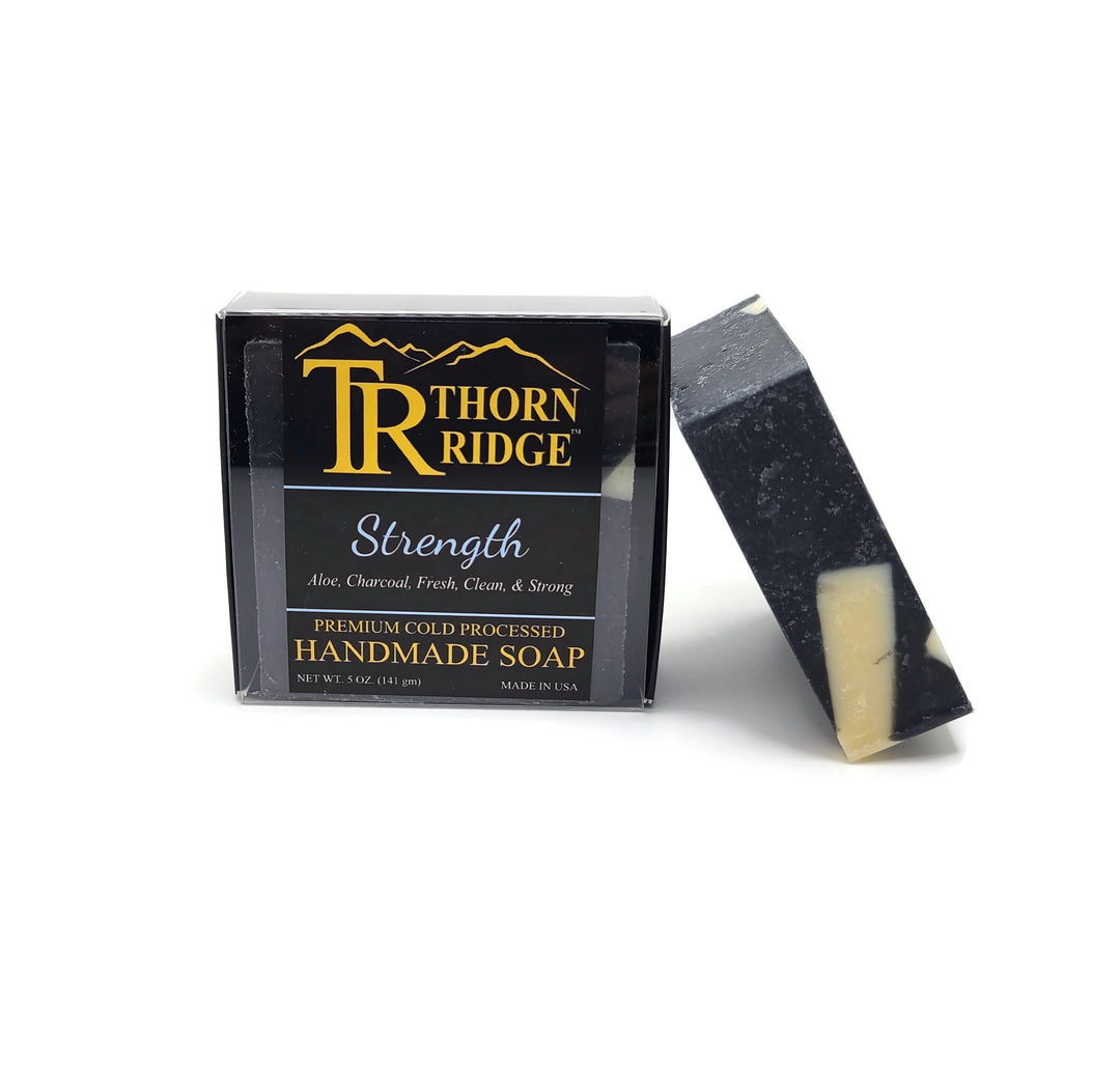 Packaging of Thorn Ridge soap labeled "Strength," described as aloe, charcoal, fresh, clean, and strong, premium cold processed, handmade, 5 oz. Made in USA.