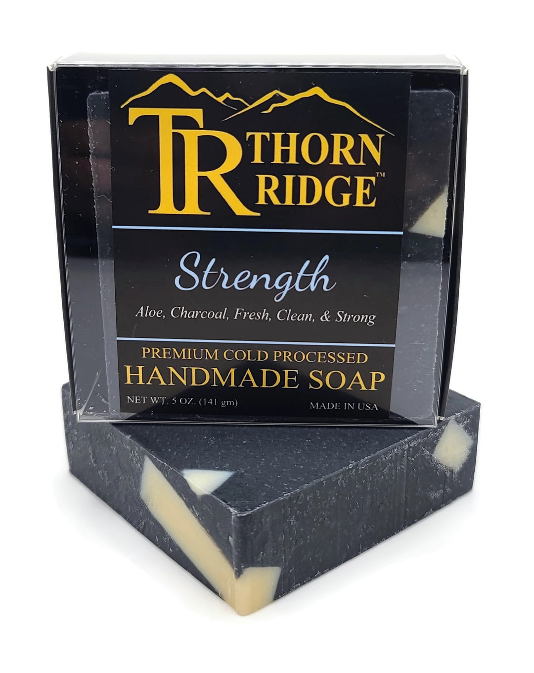 Packaging of Thorn Ridge soap labeled "Strength," described as aloe, charcoal, fresh, clean, and strong, premium cold processed, handmade, 5 oz. Made in USA.