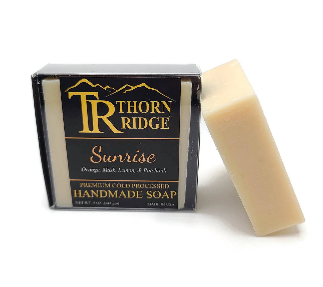 Packaging of Thorn Ridge soap labeled "Sunrise," described as orange, musk, lemon, patchouli, premium cold processed, handmade, 5 oz. Made in USA.