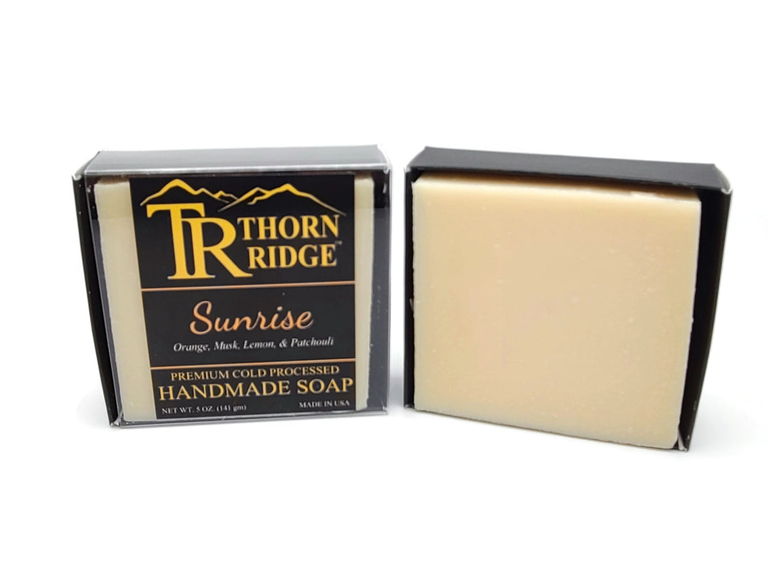 Packaging of Thorn Ridge soap labeled "Sunrise," described as orange, musk, lemon, patchouli, premium cold processed, handmade, 5 oz. Made in USA.