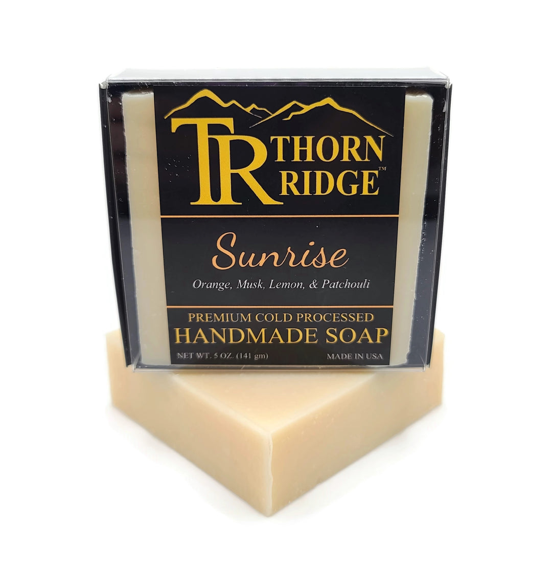 Packaging of Thorn Ridge soap labeled "Sunrise," described as orange, musk, lemon, patchouli, premium cold processed, handmade, 5 oz. Made in USA.