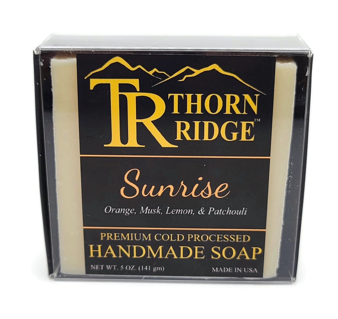 Packaging of Thorn Ridge soap labeled "Sunrise," described as orange, musk, lemon, patchouli, premium cold processed, handmade, 5 oz. Made in USA.