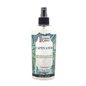 A bottle of Thorn Ridge fragrance mist labeled "Captivated," described as a cedarwood and ylang ylang scent for body, home, bathroom, and vehicles. 8 fl oz.