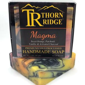 Packaging of Thorn Ridge soap labeled "Magma," described as sweet orange, patchouli, vanilla, activated charcoal, premium cold processed, handmade, 5 oz. Made in USA.
