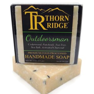Packaging of Thorn Ridge soap labeled "Outdoorsman," described as cedarwood, patchouli, tea tree, sea salt, activated charcoal, premium cold processed, handmade, 5 oz. Made in USA.