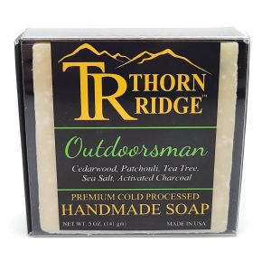Packaging of Thorn Ridge soap labeled "Outdoorsman," described as cedarwood, patchouli, tea tree, sea salt, activated charcoal, premium cold processed, handmade, 5 oz. Made in USA.