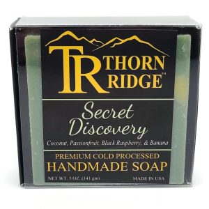 Packaging of Thorn Ridge soap labeled "Secret Discovery," described as coconut, passionfruit, black raspberry, banana, premium cold processed, handmade, 5 oz. Made in USA.