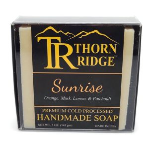 Packaging of Thorn Ridge soap labeled "Sunrise," described as orange, musk, lemon, patchouli, premium cold processed, handmade, 5 oz. Made in USA.