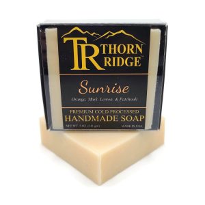 Packaging of Thorn Ridge soap labeled "Sunrise," described as orange, musk, lemon, patchouli, premium cold processed, handmade, 5 oz. Made in USA.